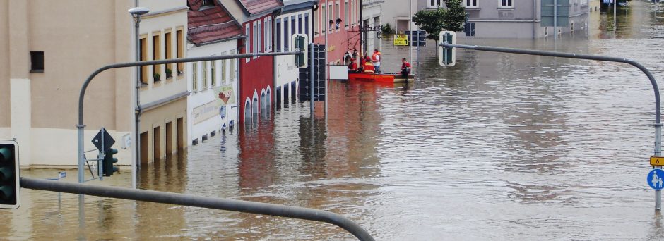 A flooded street in Germany with a rescue boat pulled up to a window to evacuate people from a building.
