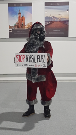 A coal-blackened Santa Claus wearing a gas mask walks around at the COP15 meeting in Copenhagen in 2009, carrying a cardboard sign that says "Stop fossil fuel."