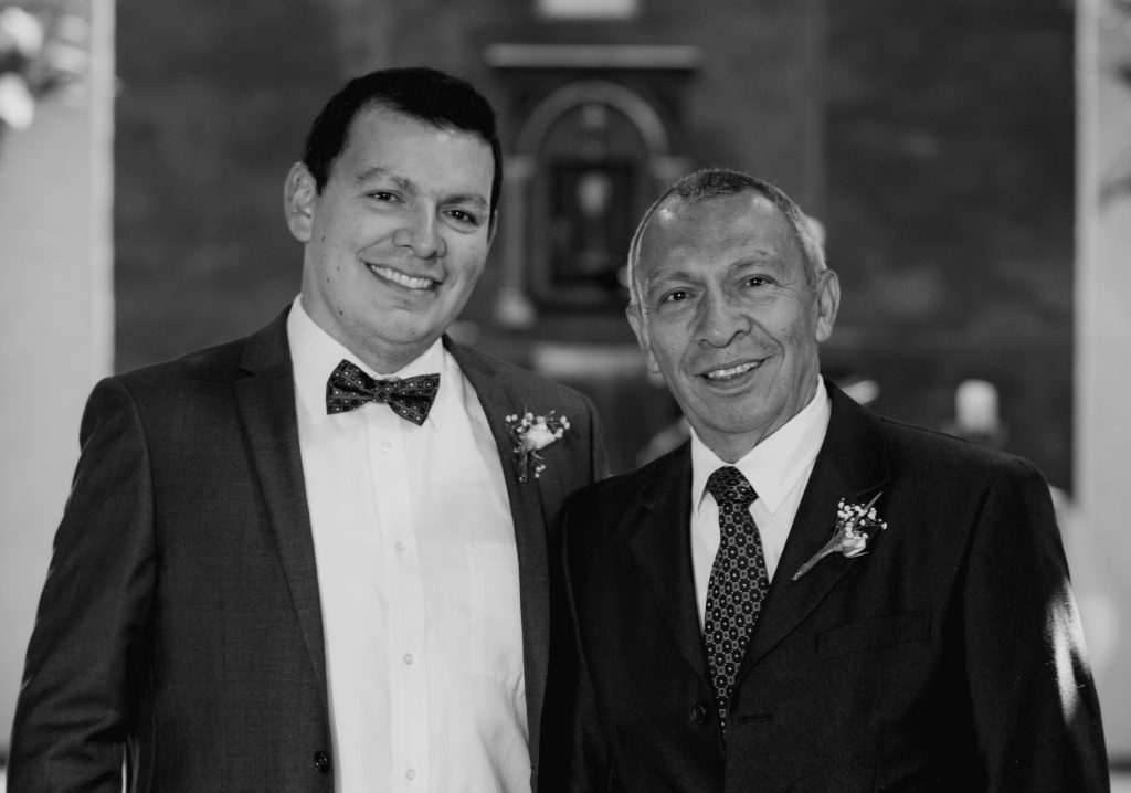 Daniel Ruiz Carrascal and his father wear suits with flowers pinned to their lapels at a wedding. The photo is in black and white.